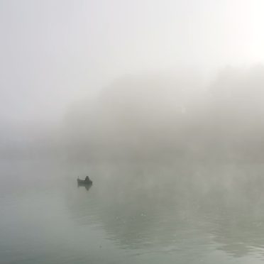 Photo où l'on voit une barque au loin avec une personne dedans, qui a l'air seule. Cette barque est à peine visible car entourée par du brouillard. Cette photo illustre le poème qui l'accompagne et qui est une métaphore de la vie, et de la barque qui va nous permettre de traverser des flots et des torrents. Photo prise par Armelle LAMBERT RODRIGUES, thanadoula.