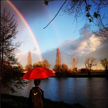 Cette photo montre un arc en ciel qui semble se poser sur un parapluie tenu par un petit garçon. Le ciel est sombre d'un côté, et il est clair de l'autre. Un peu comme un métaphore, cette photo montre l'abri que mettre à disposition une thanadoula à une personne hypersensible, quand elle traverse une phase de deuil, un lieu calme et serein à l'abris de tumultes de la vie.