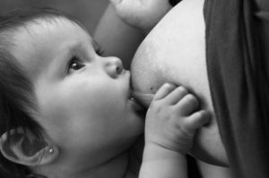 photo où l'on voit un bébé en train d'allaiter et qui échange du regard avec sa maman