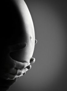 ventre de femme enceinte avec ses mains posées sur son ventre en rentrant en contact avec son bébé